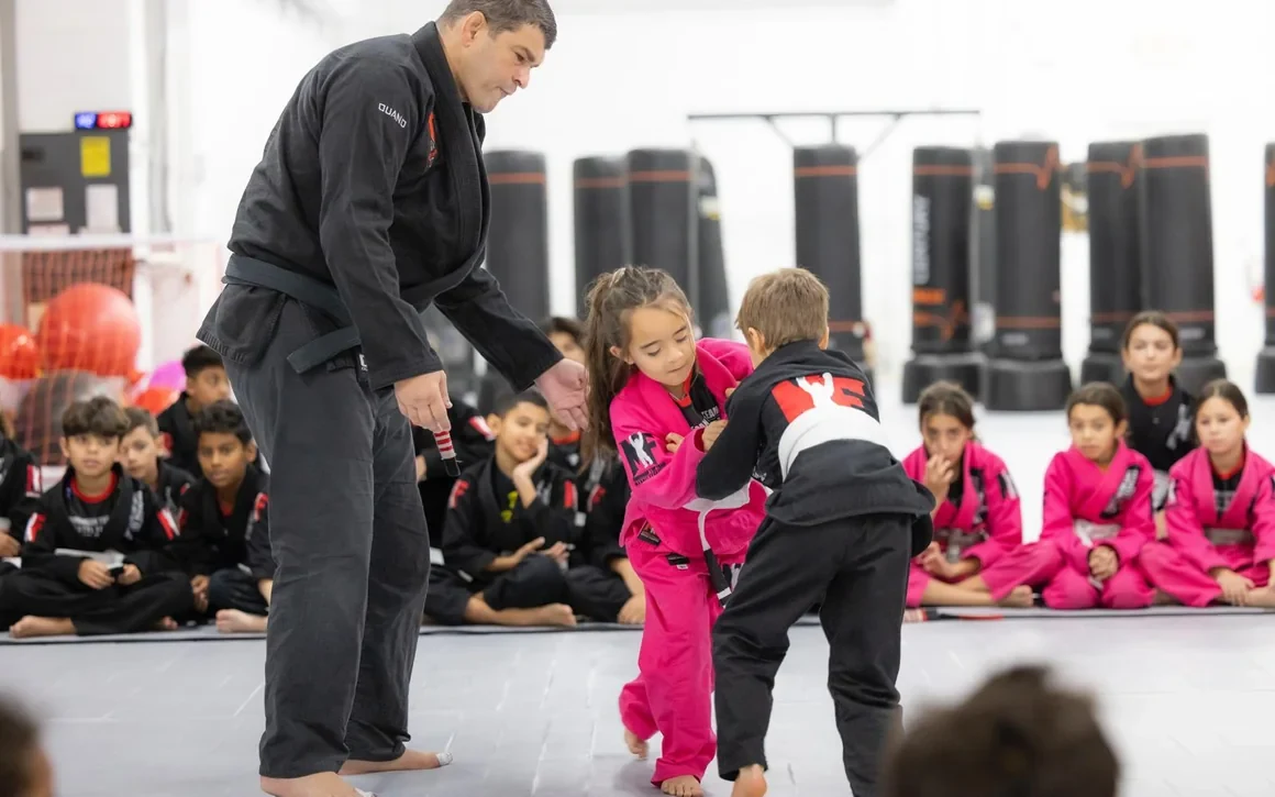 Coach Marcel teaching a young girl and boy in gis during a Kids Jiu-Jitsu class at ATT Winter Garden